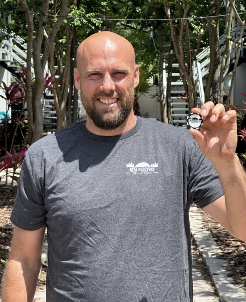 man smiling with sober chip at Real Recovery Noth Tampa